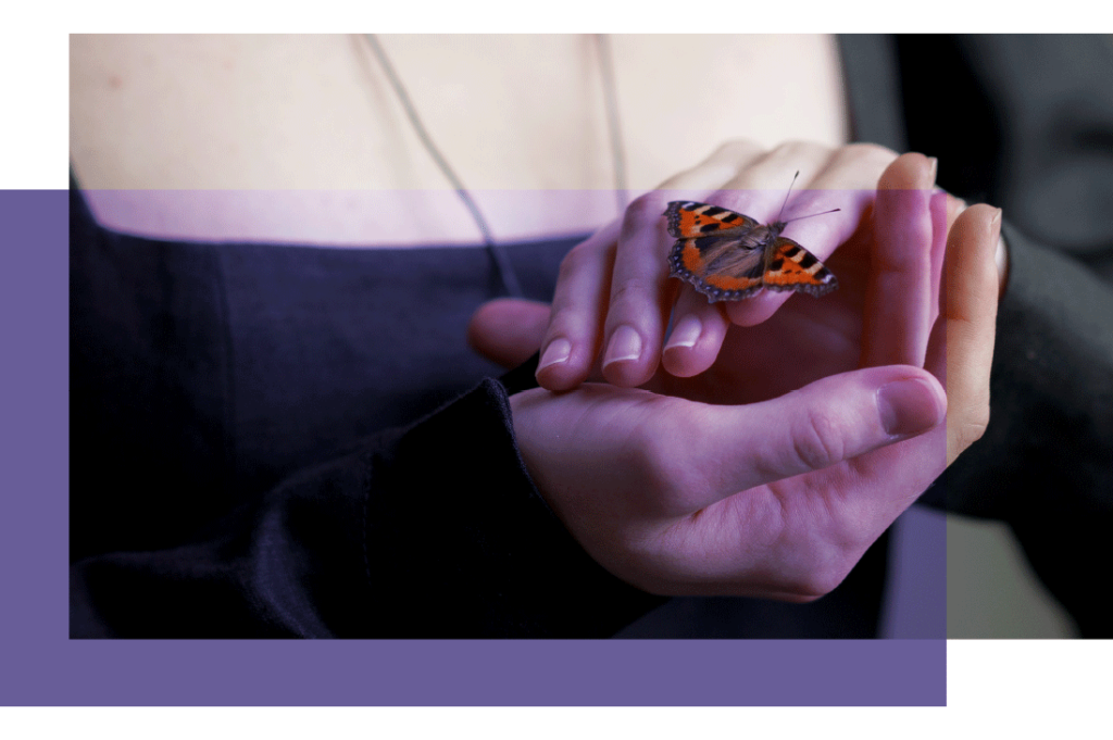 Jeune femme qui tient un papillon entre ses mains.