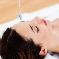 Photo d'une femme sous hypnose avec un pendule au dessus de sa tête.